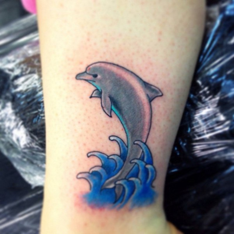 Simple Cartoon Like Colored Little Dolphin Tattoo On Arm Tattooimagesbiz 