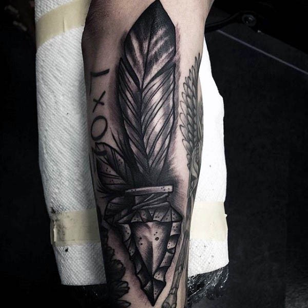 3D like antic arrow head tattoo on forearm combined with lettering