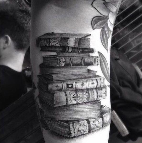 Tatuaje en el antebrazo, pila de libros diferentes antiguos
