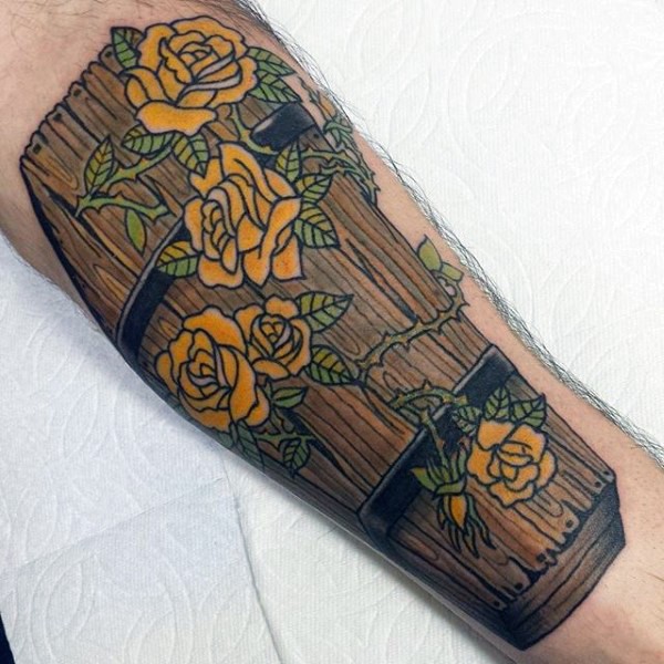 Tatuaje en el antebrazo, ataúd de madera decorado con rosas amarillas