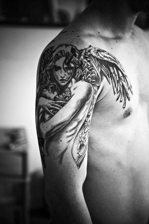 Tatuaje  negro blanco en el hombro, ángel triste con flores
