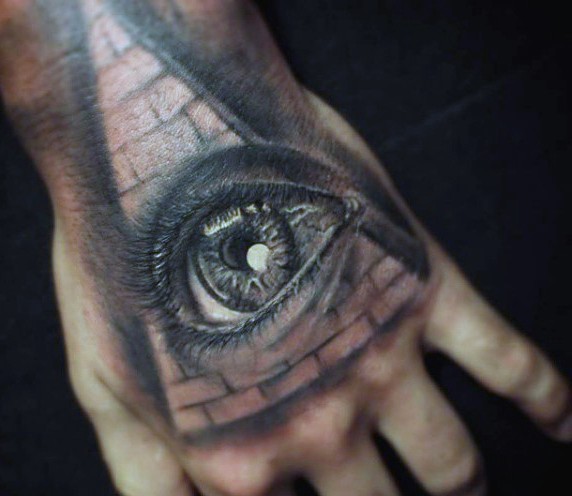 3D like very detailed human eye tattoo on hand combined with big pyramid