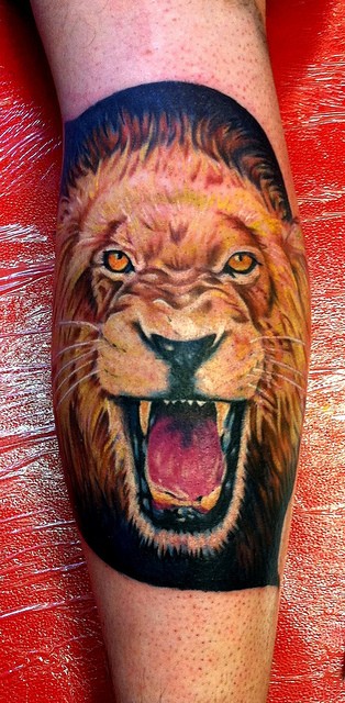 Tatuaje en la pierna, león en el fondo negro