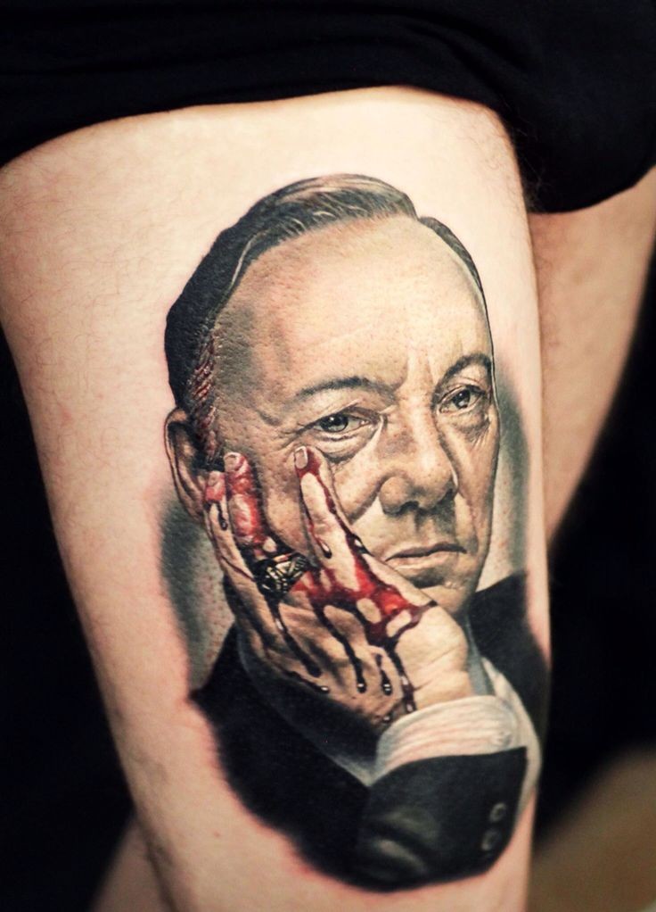 Tatuaje en el muslo,  retrato realista de hombre con la mano en sangre
