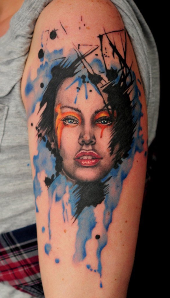 Tatuaje en el brazo,
rostro de mujer atractiva con manchas de pintura