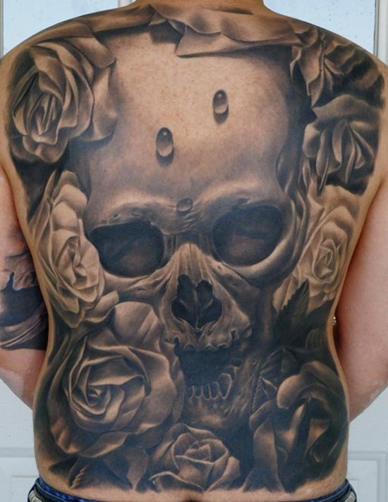 Tatuaje en la espalda completa, cráneo espantoso enorme entre flores