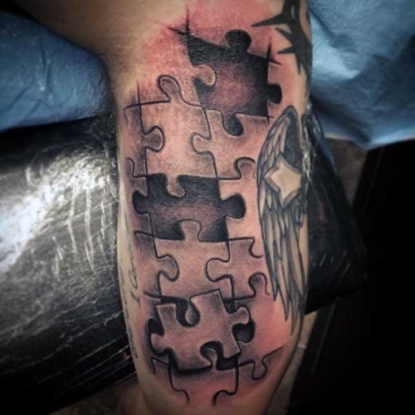 3D style black and white arm tattoo of puzzle pieces