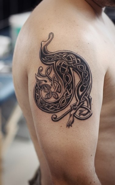 3D style black and white dragon shaped Celtic tattoo on shoulder