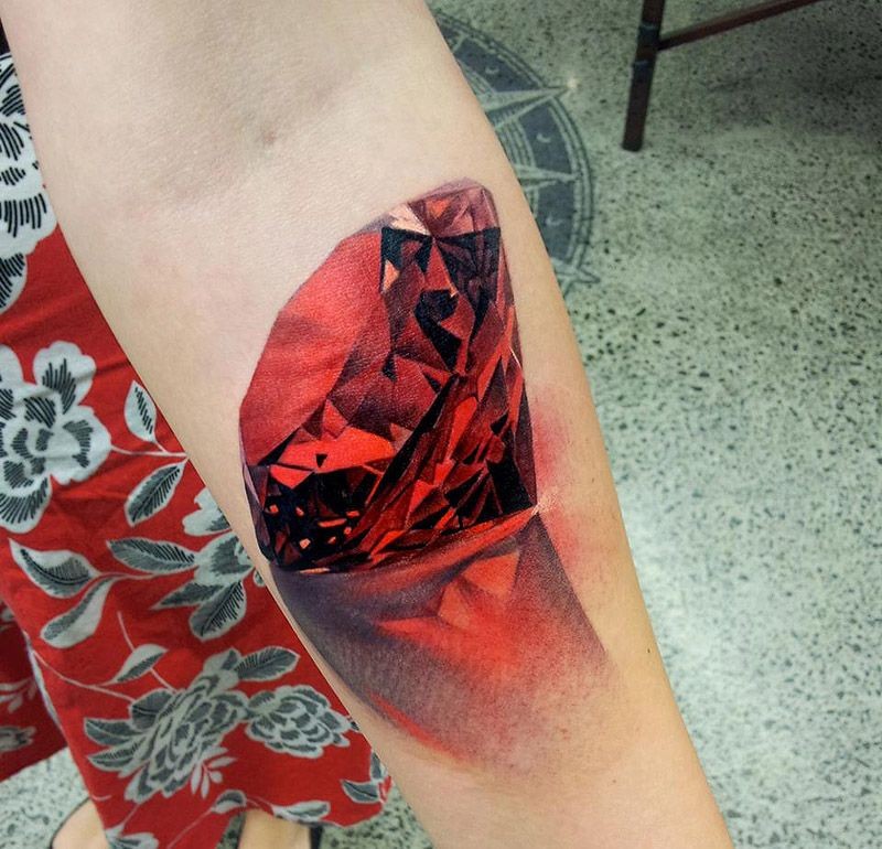 3D style colored forearm tattoo of pure red diamond