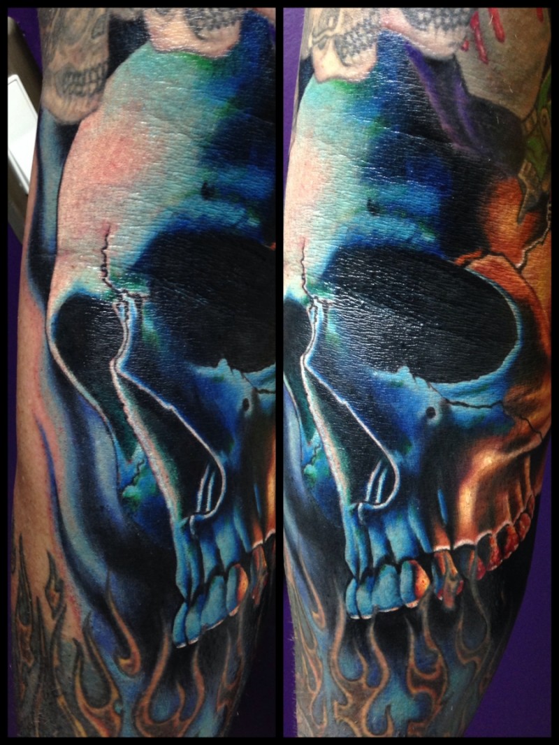 Tatuaje en el antebrazo, cráneo azul agrietado  con llamas