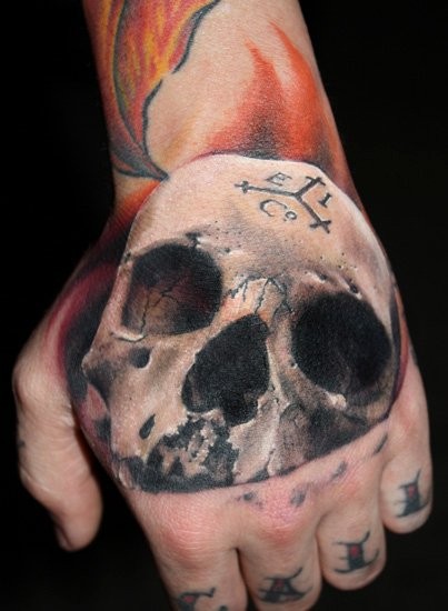 Tatuaje en la mano, 
cráneo humano agrietado volumétrico