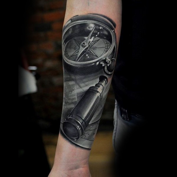 Tatuaje en el antebrazo, compás volumétrico con telescopio y  mapa del mundo vieja