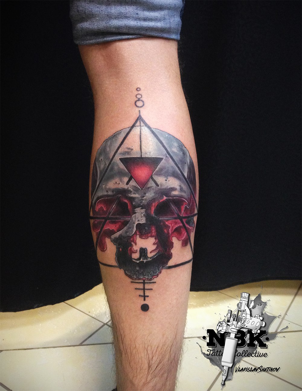 Tatuaggio astratto con teschio metallico sulla gamba