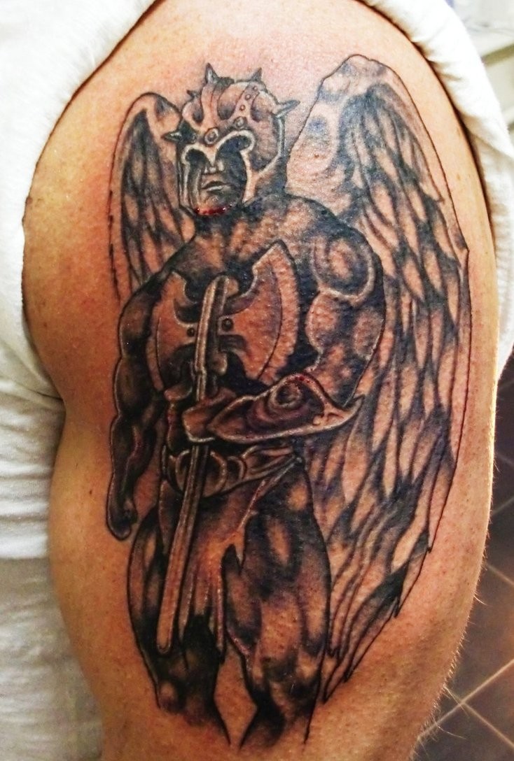 Tatuaje  de guerrero con alas y hacha en el brazo