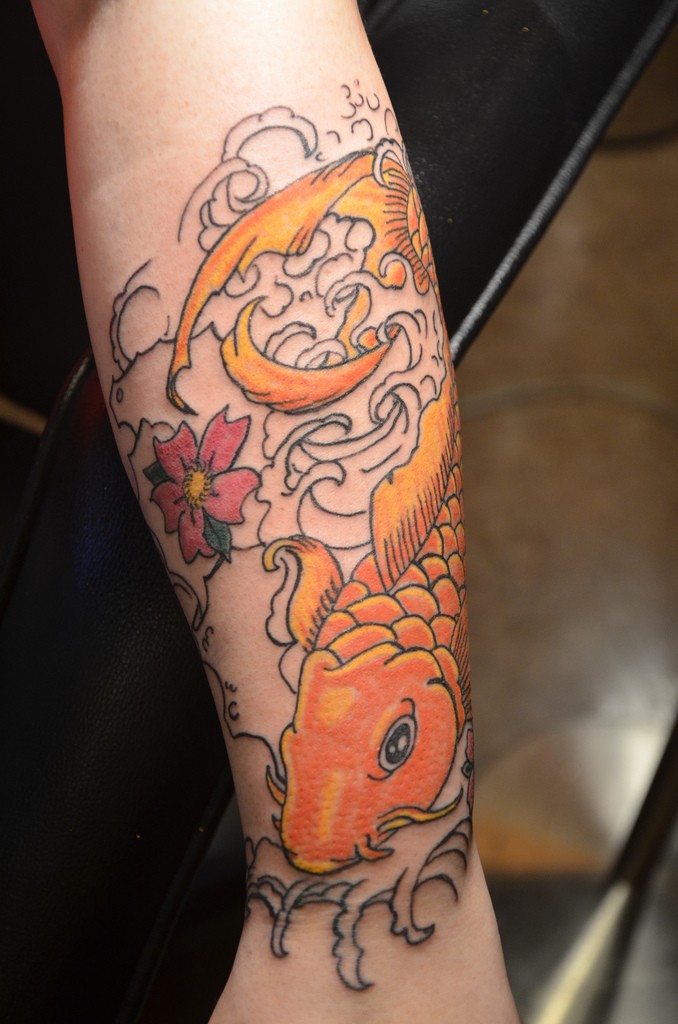Awesome golden fish in waves with flower tattoo sleeve on forearm