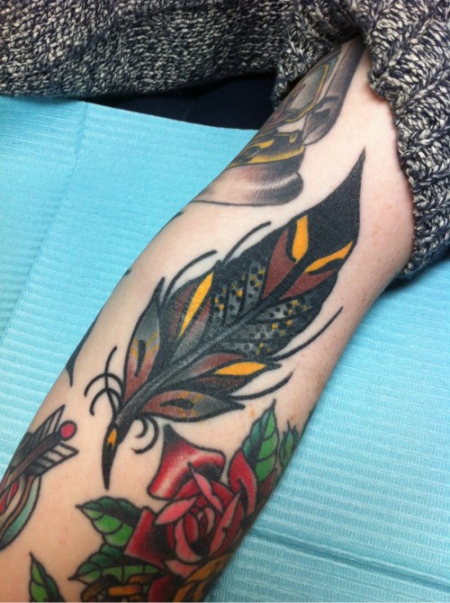 Tatuaje en el antebrazo, pluma hermosa con flores, old school