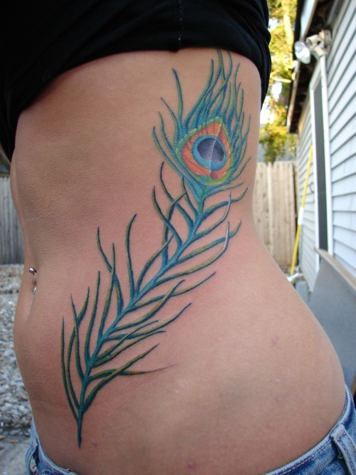Beautiful thin blue peacock feather tattoo on side