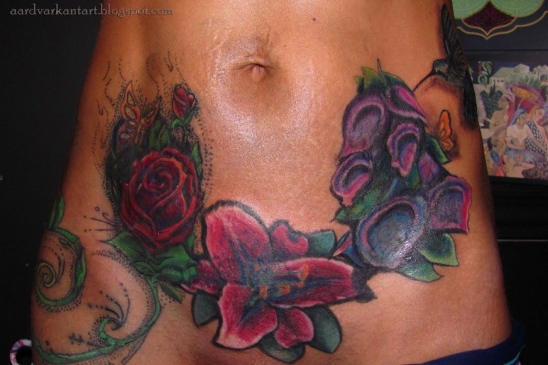 Beautiful vivid-colored exotic flowers tattoo on belly