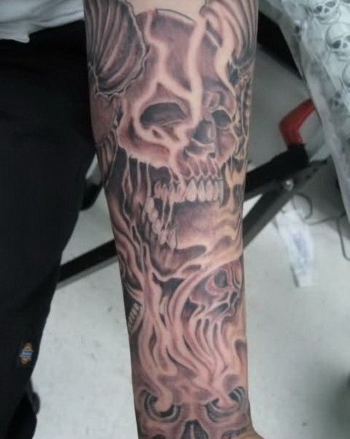 Black-and-white angry horned skull tattoo sleeve on forearm