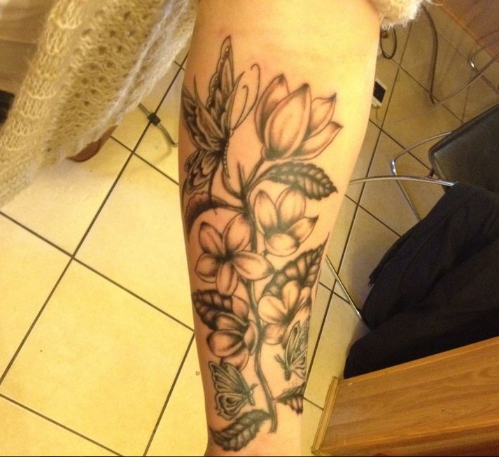 Black-and-white jasmine flower and butterfly tattoo on arm