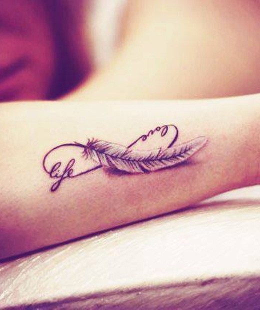 Black-and-white love and life quote with feather tattoo on arm