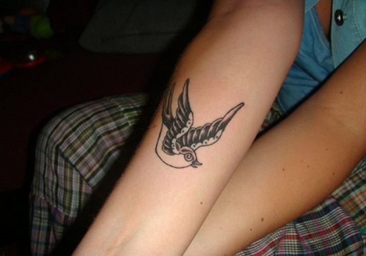 Black-and-white womens bird tattoo on forearm