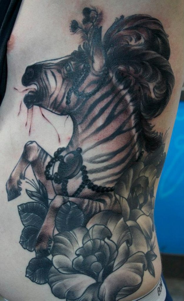 Black-and-white zebra with flowers and fethers tattoo on side