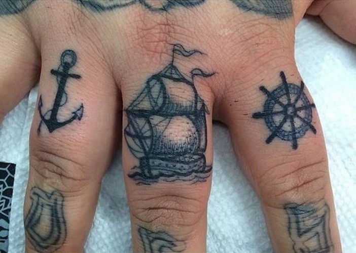 Tatuaje  de ancla, barco y timón en los dedos