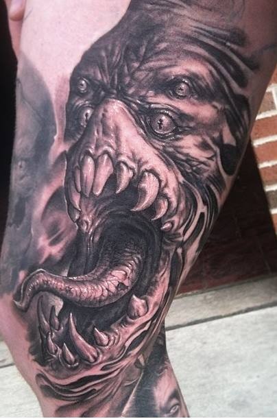 Tatuaje estilo muslo negro y gris detallado de cara de monstruo