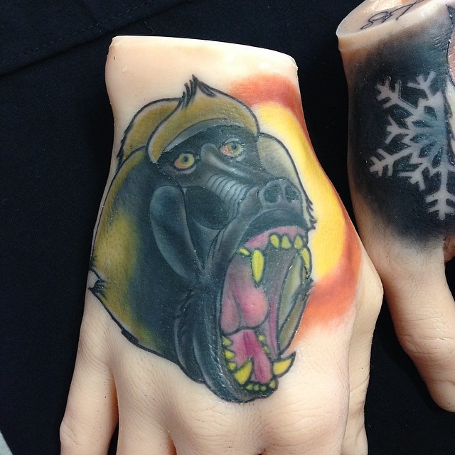 Tatuaje en la mano,  babuino enfadado y sol brillante
