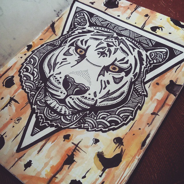 Brown-eyed ornamented tiger head on triangle background tattoo design