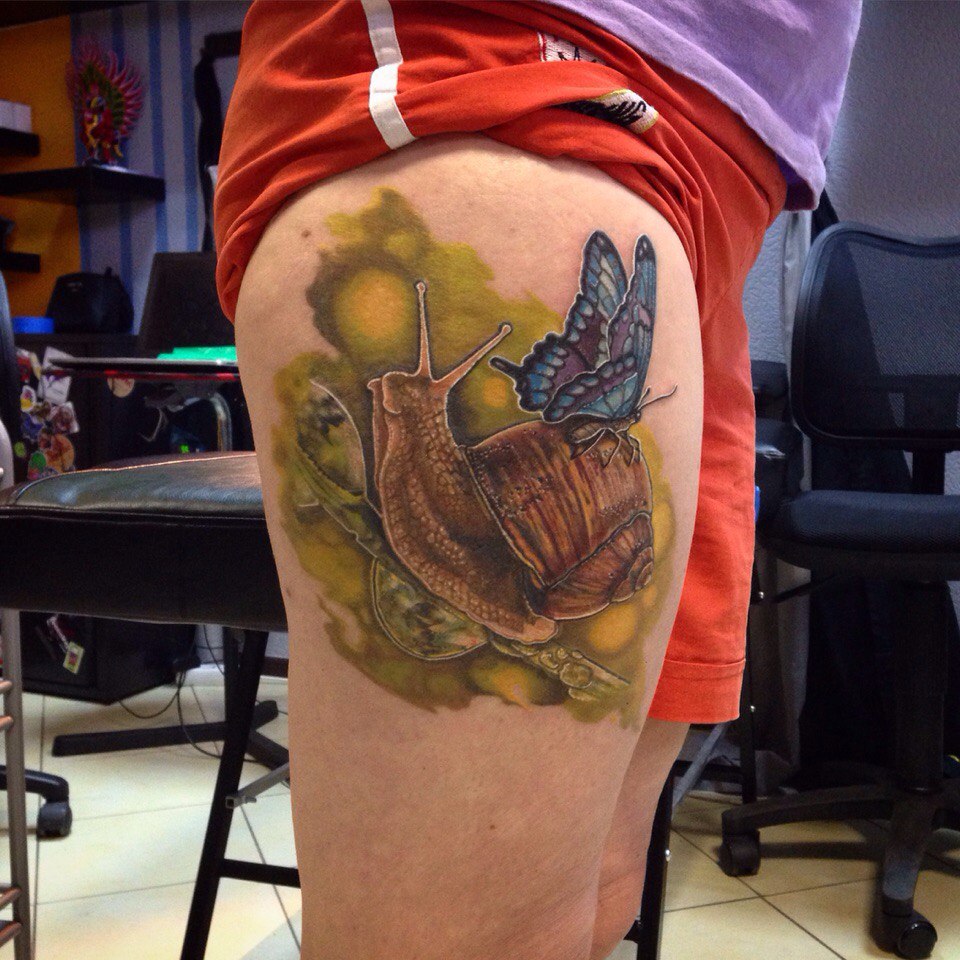 Butterfly on snail tattoo on leg