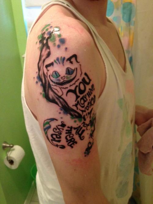 Tatuaggio colorato sul deltoide il disegno in forma di gatto e l&quotalbero