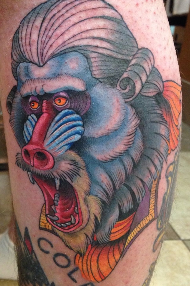 Color-ink baboon head in wig tattoo on leg