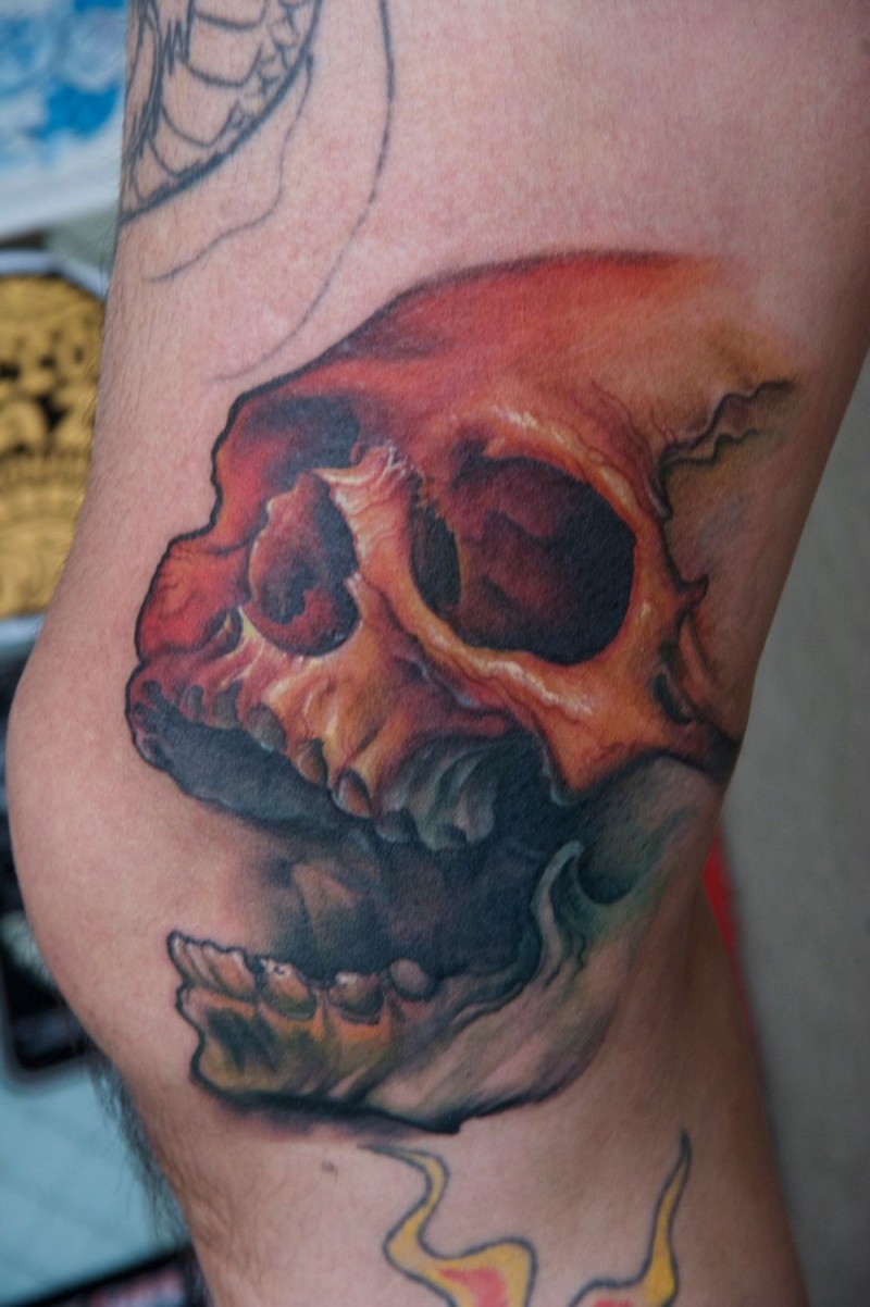 Colored skull with open jaw tattoo on knee
