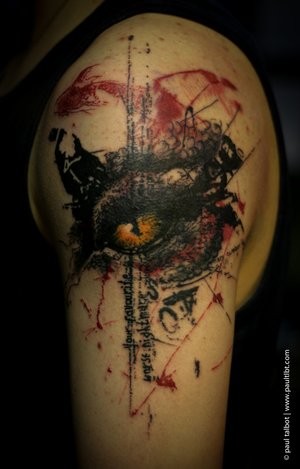 Colored trash polka style upper arm tattoo of demonic eye and lettering