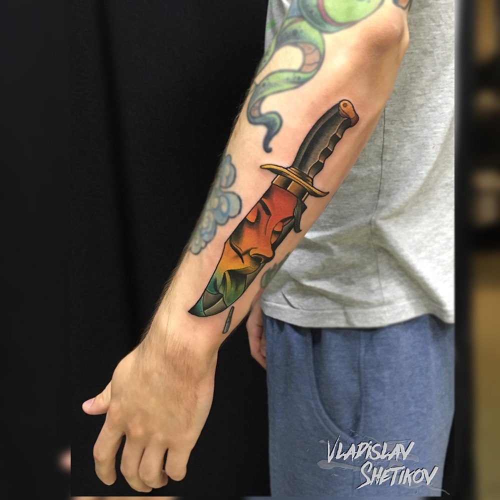 Colorfull tattoo with knife and girl face on arm