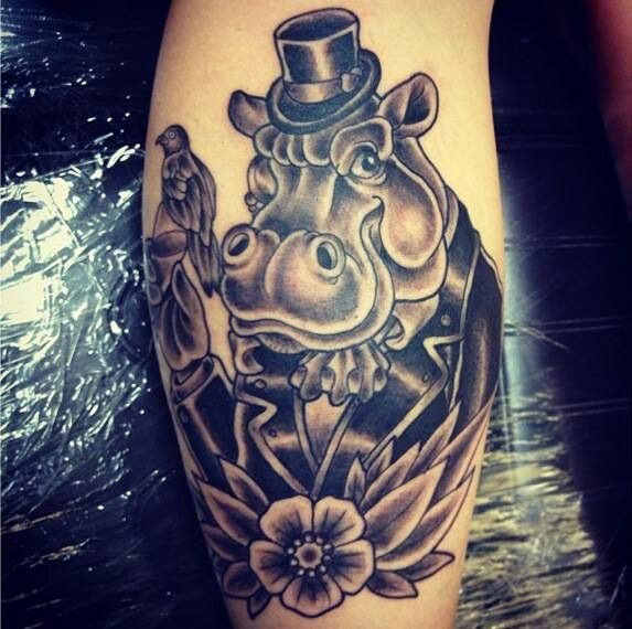 Cool old school black-ink hippo in hat with bird and flower tattoo on arm