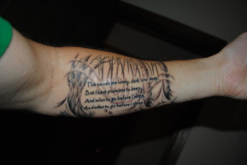 Tatuaje en el antebrazo, inscripción larga en el fondo de árboles