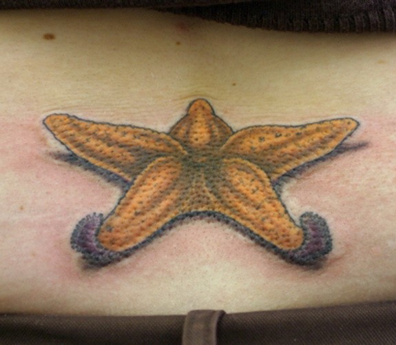 Cool yellow lying starfish tattoo on lower back