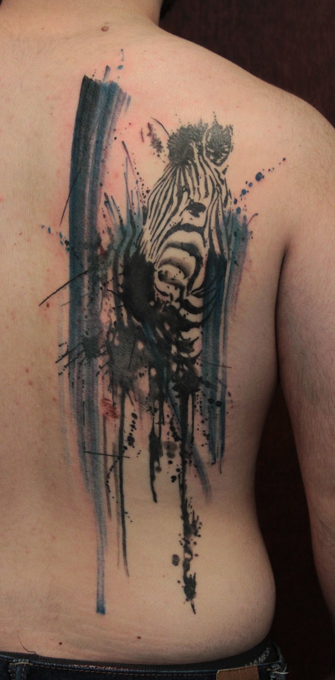 Tatuaje en la espalda,
cebra realista con manchas de pintura