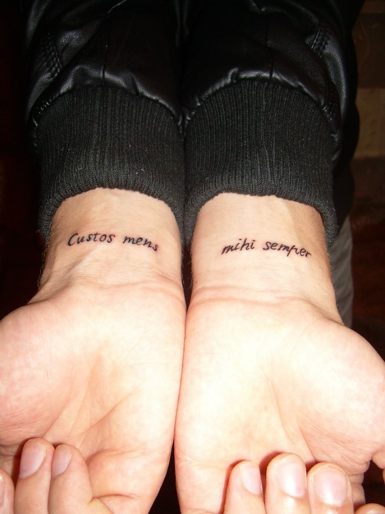 Tattoo mit Zitat auf Lateinisch &quotMein Beschützer hütet mich" auf Armen