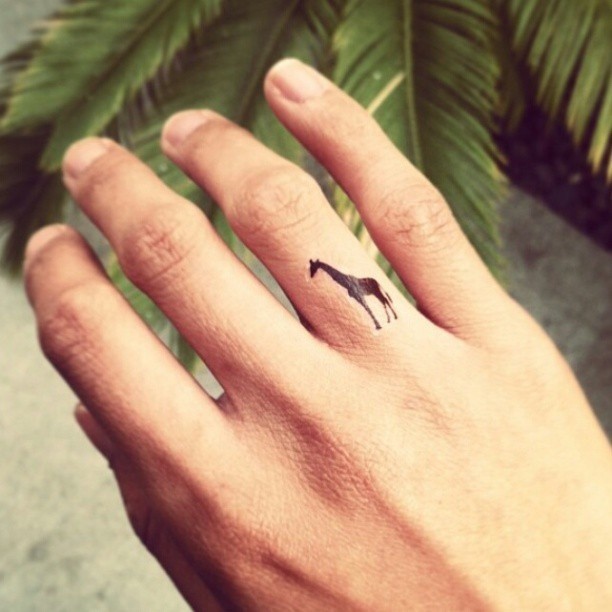 Cute black little giraffe tattoo on finger