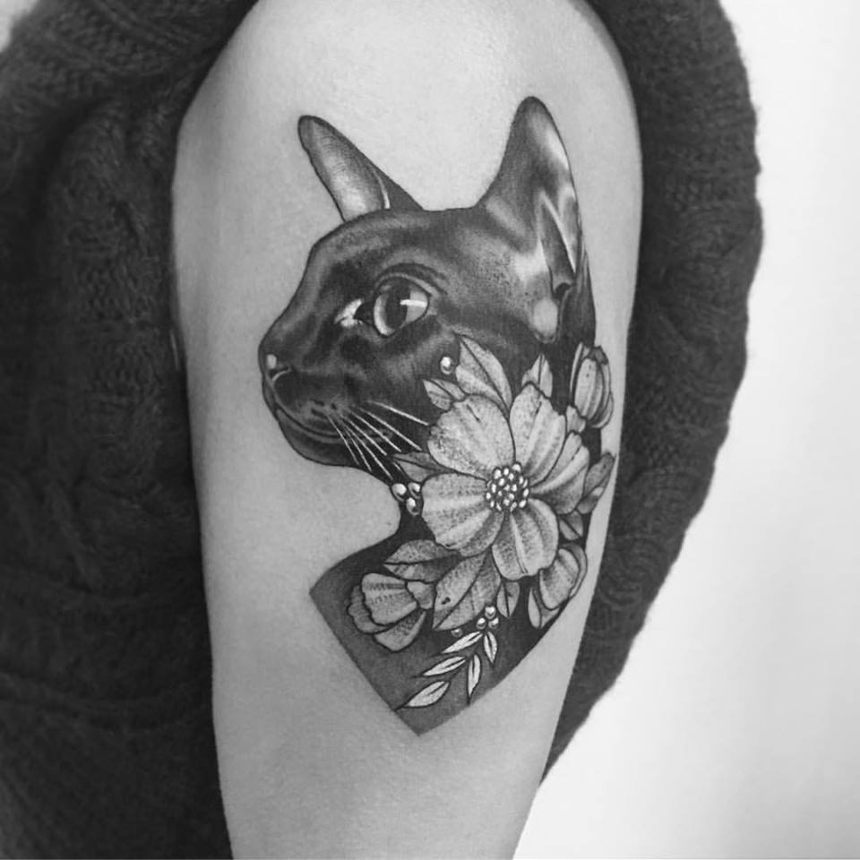 Tatuagem feminina gira com gato e flor