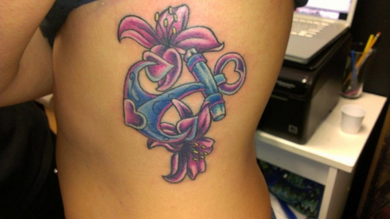Cute pink-and-blue anchor with lilies tattoo on rib-side