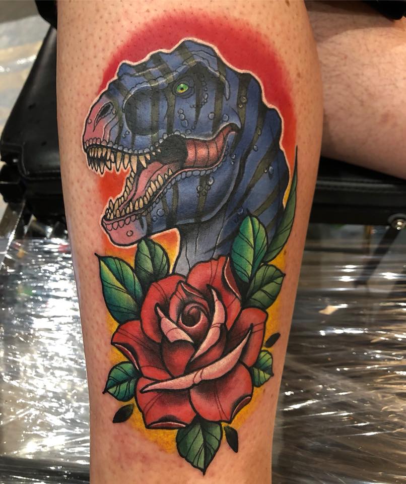 Dinosaur head and red rose tattoo on leg