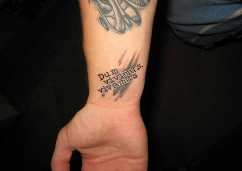 citazione latina scritta tatuaggio su braccio
