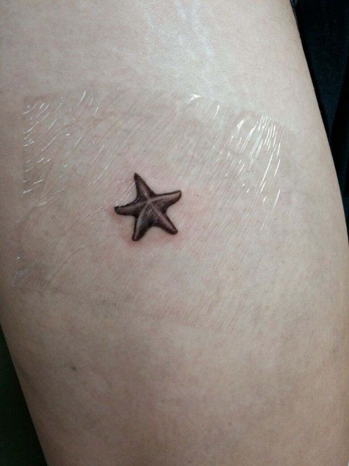 Elegant girly black-ink starfish tattoo on arm
