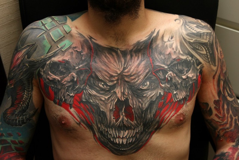 Enorme tatuagem no peito colorido de caveira monstro combinado com crânios humanos