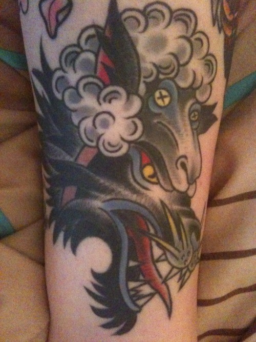 Evil wolf in sheep skin tattoo on arm